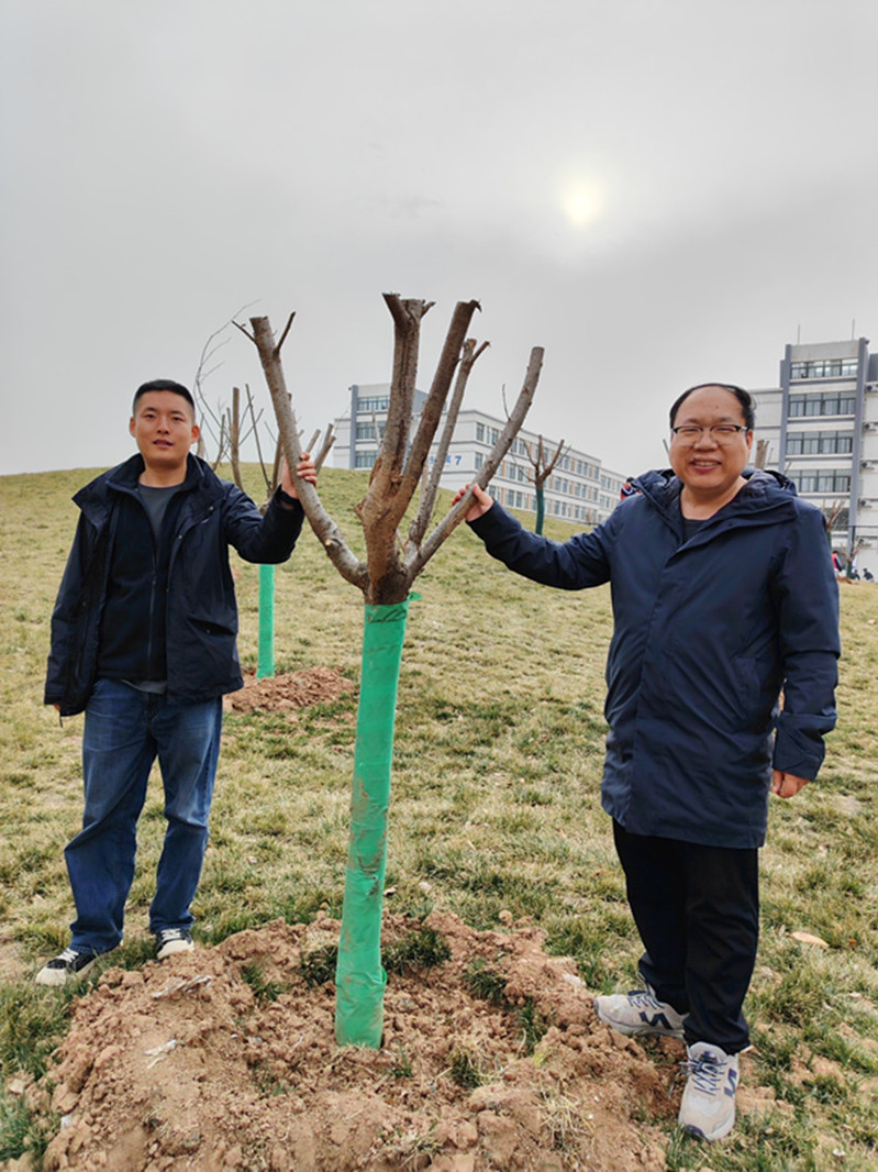 与亲手栽种下的树苗合影留念
