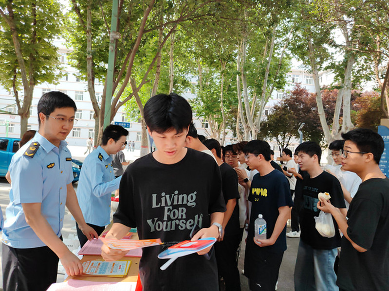 学生领取宣传手册后认真翻阅学习，现场持续向青年群体科普拒绝药物滥用、规范安全用药相关常识。
