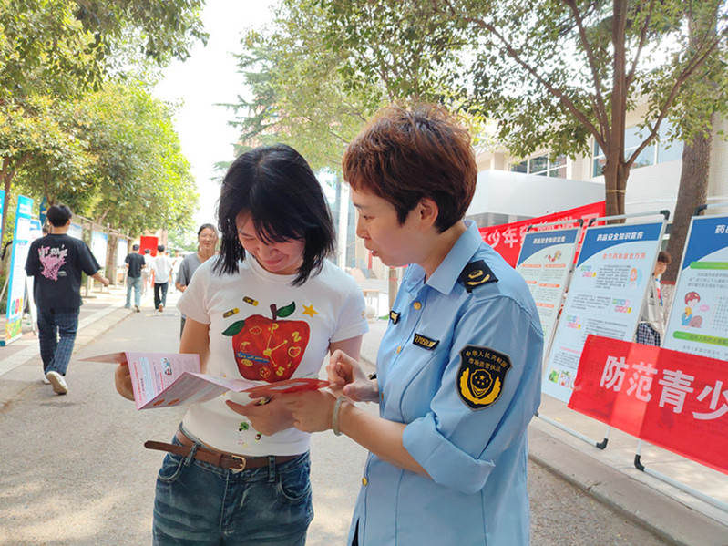 市场监管执法人员一对一为在校女学生讲解药品安全宣传手册，细致科普青少年安全用药、防范药物滥用相关知识。