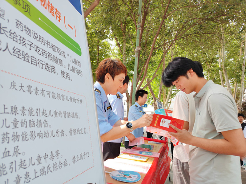 工作人员向青年学生发放科普宣传折页，结合展板内容讲解用药禁忌、麻精药品危害等禁毒用药安全要点。